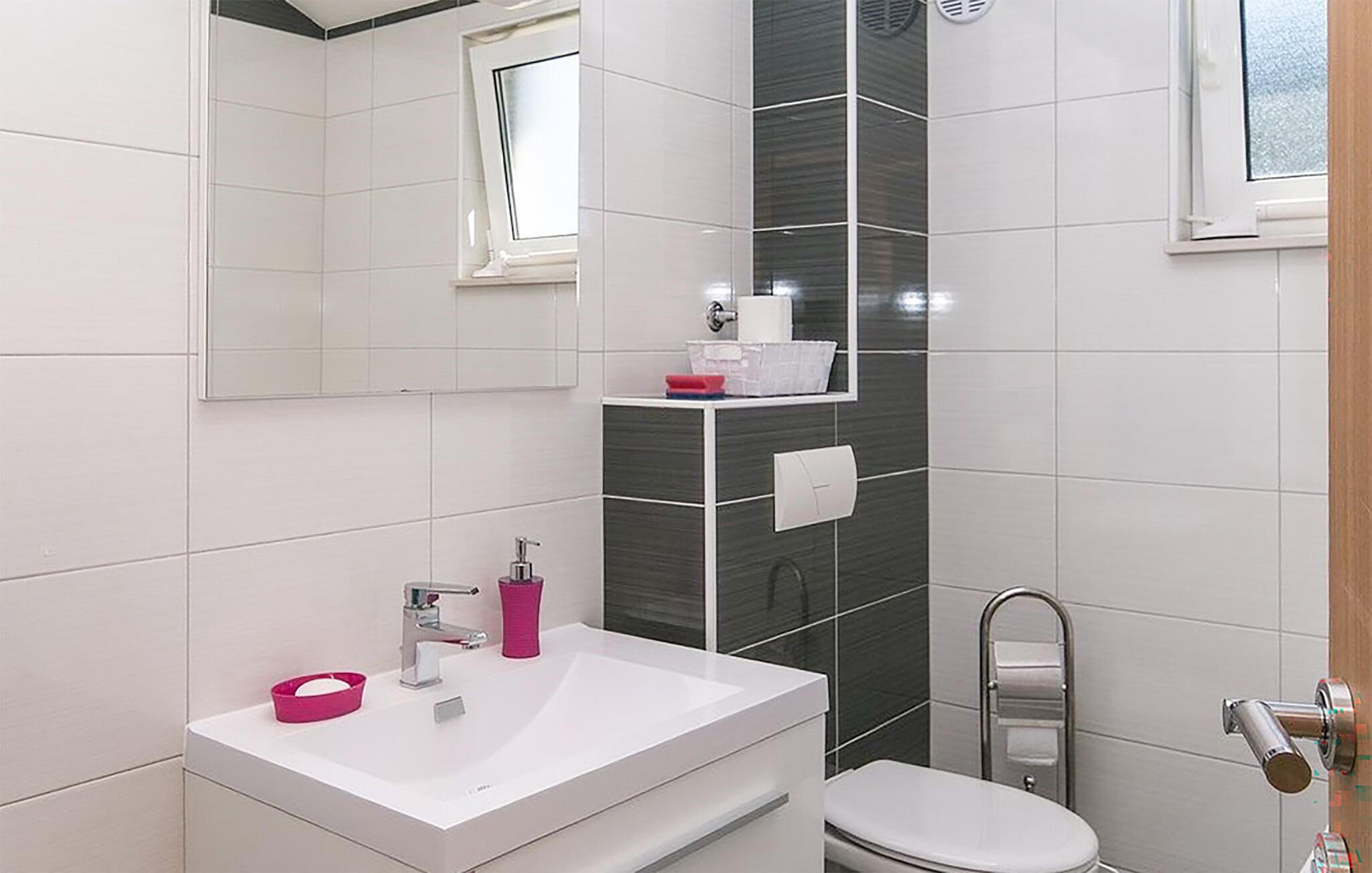 A modern bathroom with a white sink, a toilet, and a mirror.