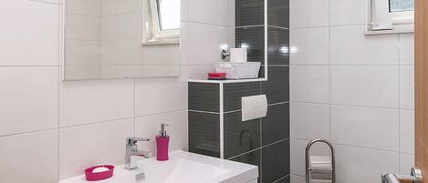 A modern bathroom with a white sink, a toilet, and a mirror.