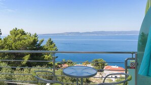 A balcony with a table and chairs, overlooking a body of water and distant land. - 2 bedroom awesome apartment in Brela (Brela)