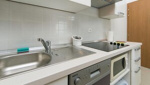 Ett modernt kök med diskhoar i rostfritt stål, en inbyggd ugn och en mikrovågsugn.
