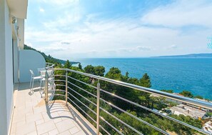A balcony with a metal railing overlooking a body of water and greenery. - Lovely apartment in Brela with WiFi (Brela)