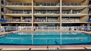 Um hotel com vários andares e uma piscina em frente.