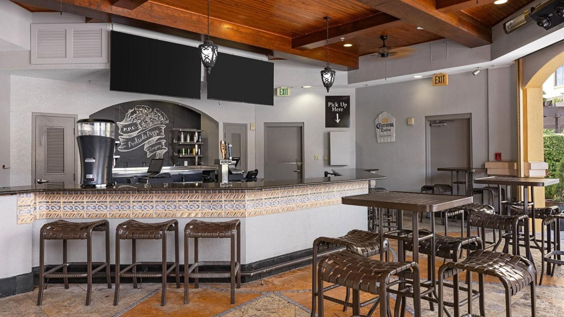 A restaurant with a bar area, bar stools, and a counter with a pizza menu.