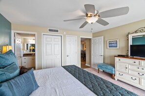 Ein Schlafzimmer mit Bett, Deckenventilator, Kommode und Fernseher.