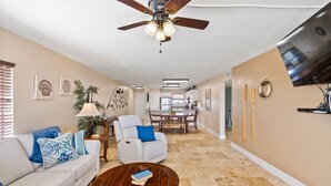 A spacious living room with a ceiling fan, a dining area, and a kitchen in the background. - Welcome to Grandview – Laguna Reef Unit 414 (Rockport)