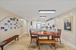 A spacious kitchen with white cabinets, a central island, and a dining area with a wooden table and chairs.
