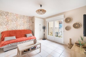 A living room with a sofa, a coffee table, a fan, and a view of the outside balcony.