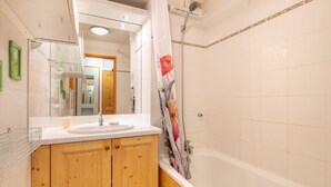 Ein Badezimmer mit einem Holzbadschränken, einem Waschbecken, einem Spiegel und einer Dusche mit einem Blumenvorhang.