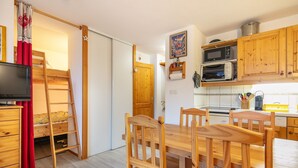 Eine kleine Küche mit Holzausstattung, einer Mikrowelle und einem Essbereich mit Tisch und Stühlen.