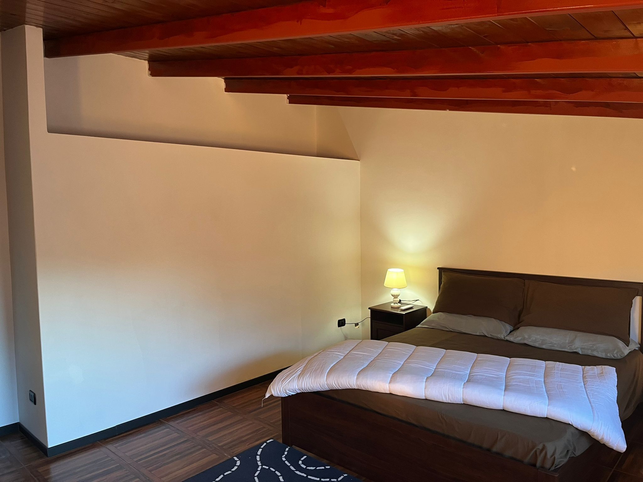 Une chambre à coucher avec un lit, une table de chevet avec une lampe et un plafond en bois.