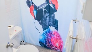 A bathroom with a shower curtain featuring a graphic of a person with headphones and a colorful ball. - Vibrant Apartment By The Beach (San Juan)