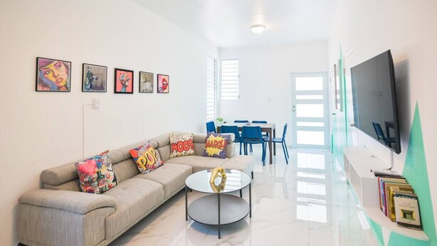 A modern living room with a sofa, coffee table, and artwork on the walls. - Vibrant Apartment By The Beach (San Juan)