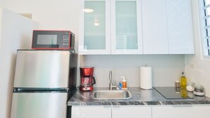 A compact kitchen with a refrigerator, a microwave, a coffee maker, and a sink. - Vibrant Apartment By The Beach (San Juan)
