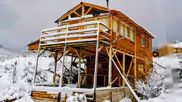 A wooden cabin with a balcony, surrounded by snow.