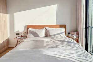 A modern bedroom with a wooden headboard, a neatly made bed, a bedside table with a lamp, and a window with curtains. - Chic, cozy studio just 2 minutes from Anfa Park and CFC. (Casablanca)