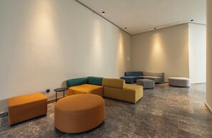 A modern lobby with a sectional sofa, ottomans, and a small table. - Chic, cozy studio just 2 minutes from Anfa Park and CFC. (Casablanca)