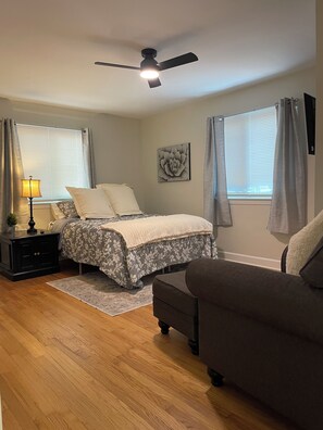 A bedroom with a bed, a nightstand, a lamp, a ceiling fan, and a window with curtains. - 2 Bedroom Duplex Vance Villa in UPTOWN Lexington! (Lexington)