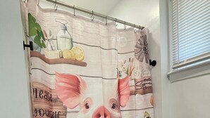 Ein Badezimmer mit einer Duschvorhangs, der einen Schwein im Eimer zeigt.
