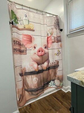 Ein Badezimmer mit einer Duschvorhangs, der einen Schwein im Eimer zeigt.