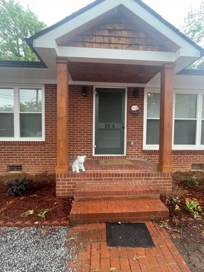 A house with a brick facade, a green door labeled '32 A', and a small white pig statue on the front steps. - 2 Bedroom Duplex Vance Villa in UPTOWN Lexington! (Lexington)
