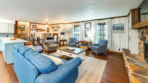 A spacious living room with a blue sofa, a wooden coffee table, and a stone fireplace. - Steps to Shore: Group Getaway on Kentucky Lake! (Hardin)