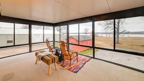 A sunroom with large windows, a wooden rocking chair, a bench, and a colorful rug. - Steps to Shore: Group Getaway on Kentucky Lake! (Hardin)