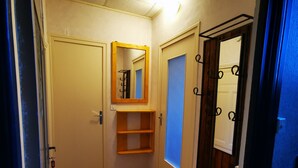 Un pasillo estrecho con una puerta de madera, un espejo y un perchero.