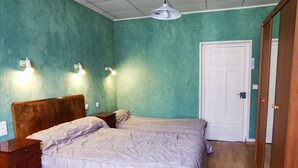 Un dormitorio con dos camas, cabeceros de madera, una puerta blanca e iluminación en la pared.