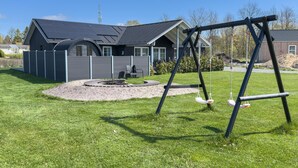 A house with a backyard, a swing set, and a fire pit. - Nice home in Grenaa with sauna (Grenaa)