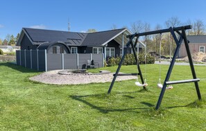 Ein Haus mit Garten, Schaukel und Feuerstelle.