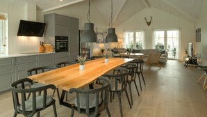 A spacious kitchen with a long wooden table and modern chairs, a built-in oven, and a large window providing natural light. - Nice home in Grenaa with sauna (Grenaa)