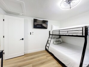 A room with a bunk bed, a television mounted on the wall, and a door. - Sunny Nokomis Getaway•Private Pool•Backyard Oasis (Nokomis)