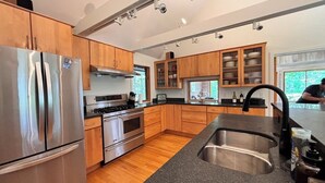 A modern kitchen with stainless steel appliances, wooden cabinets, and a granite countertop. - Lakefront Cabin Escape  Pristine Waters & Fall Foliage (Norfolk)