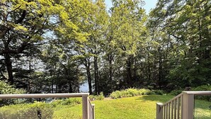 A wooden deck with a railing overlooking a grassy area and trees. - Lakefront Cabin Escape  Pristine Waters & Fall Foliage (Norfolk)