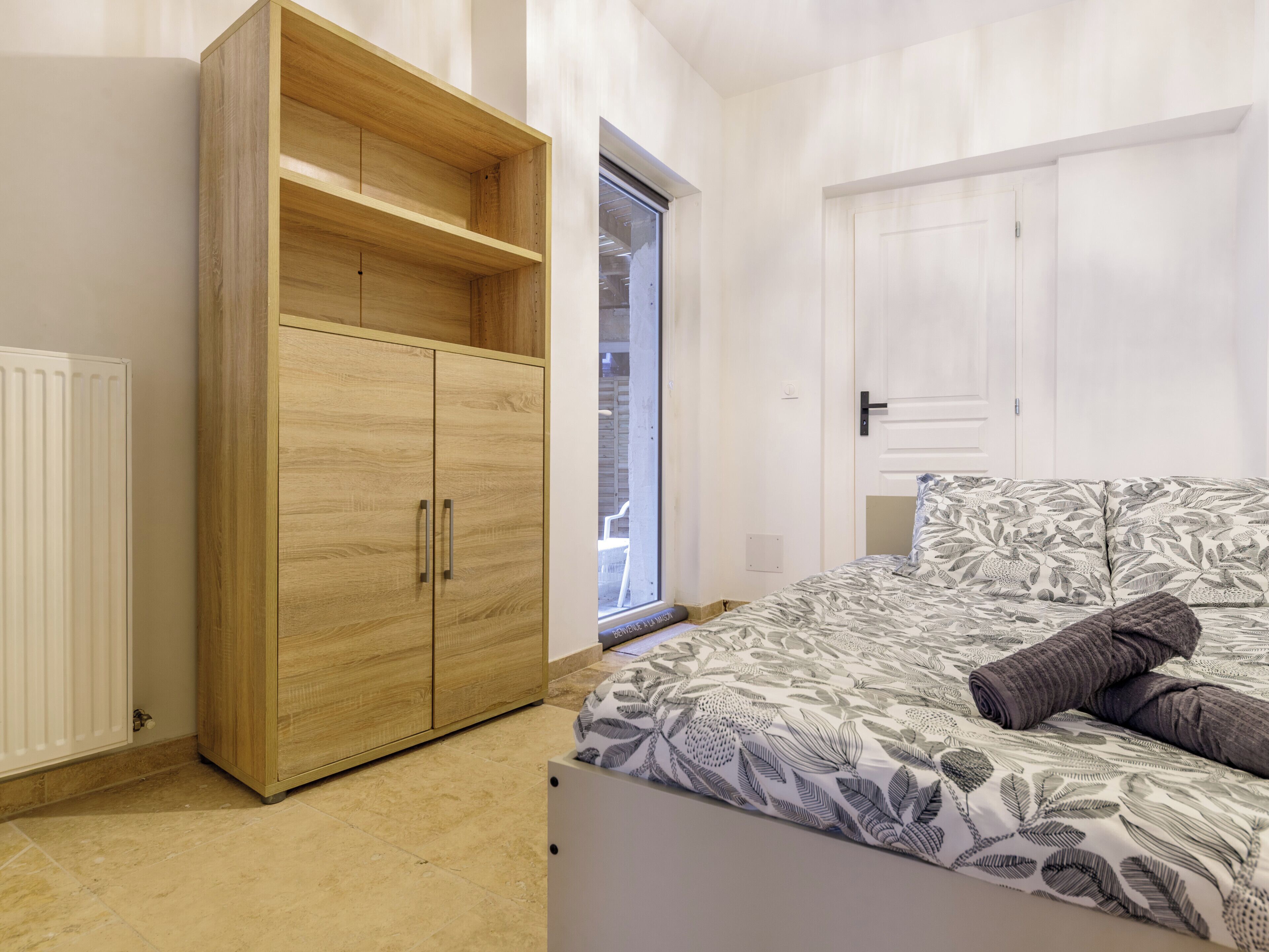 Une chambre à coucher avec un lit, une armoire en bois, un radiateur et une fenêtre.