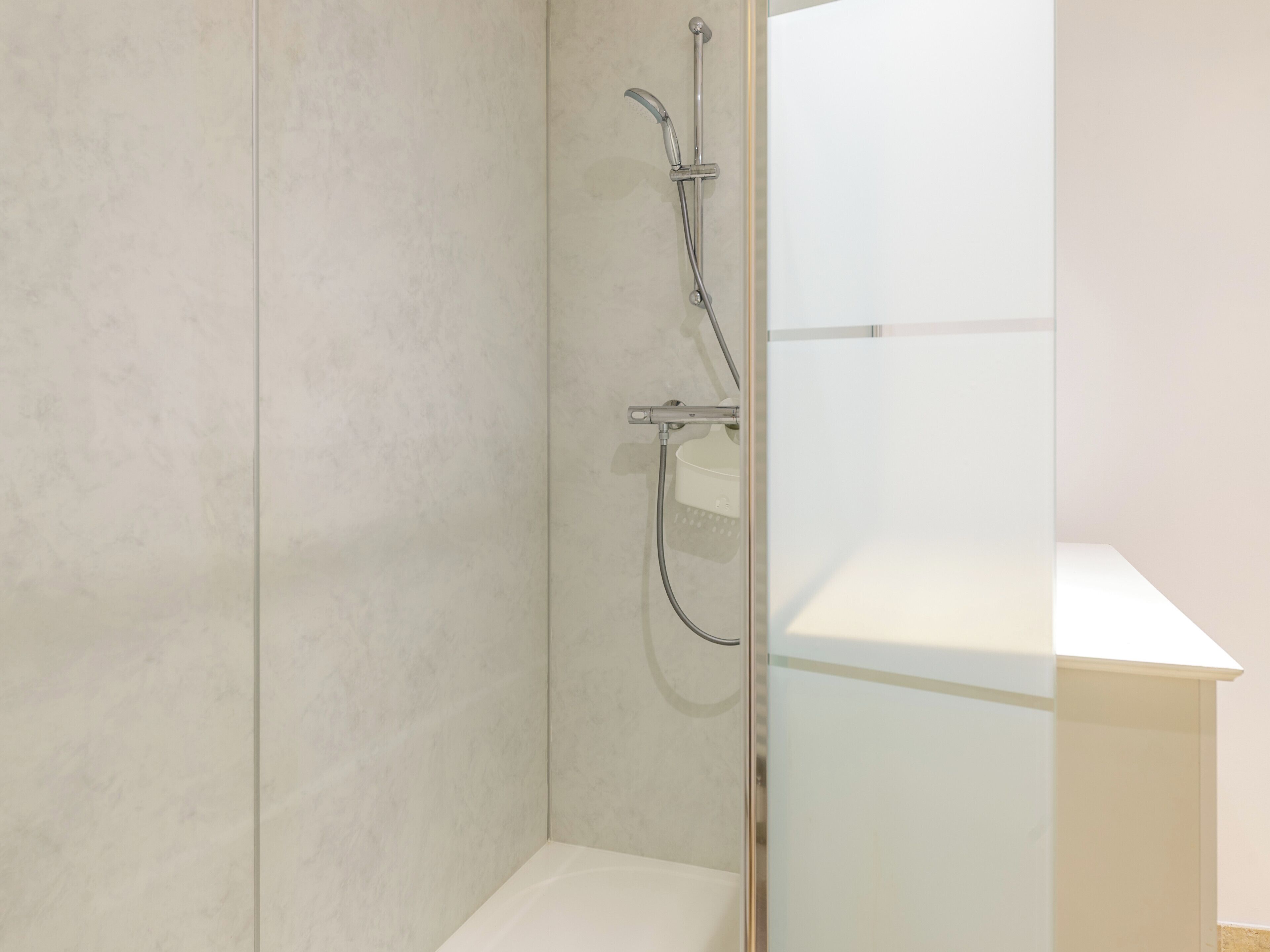 A modern bathroom with a shower, a toilet, and a glass-enclosed vanity.