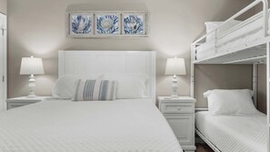 A bedroom with a bunk bed, a large bed, two bedside tables with lamps, and a wall-mounted artwork. - Condo With Gulf View Direct Beach Access, Indoor/outdoor Pool (Orange Beach)