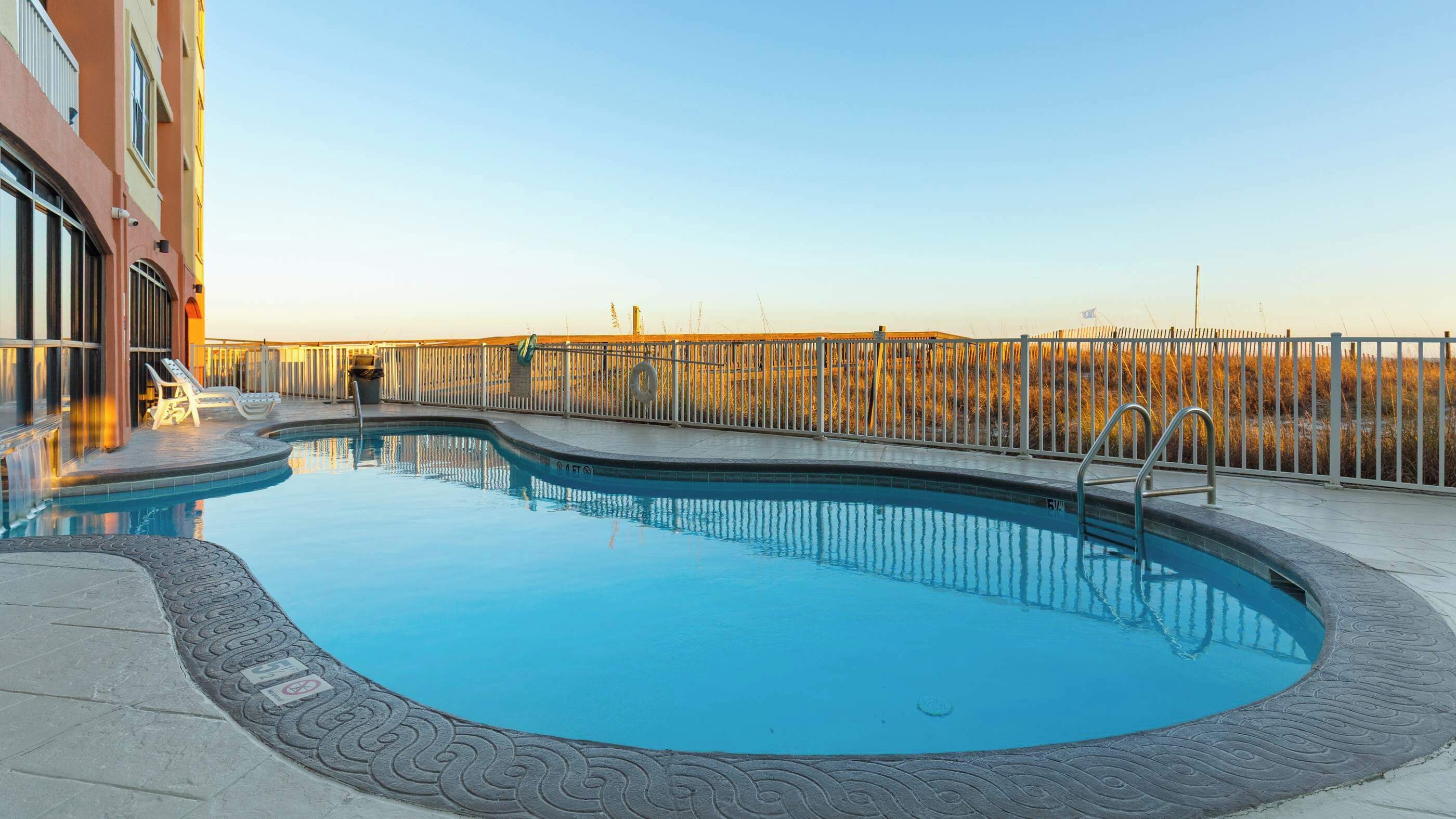 A swimming pool with a curved edge, surrounded by a patterned walkway.