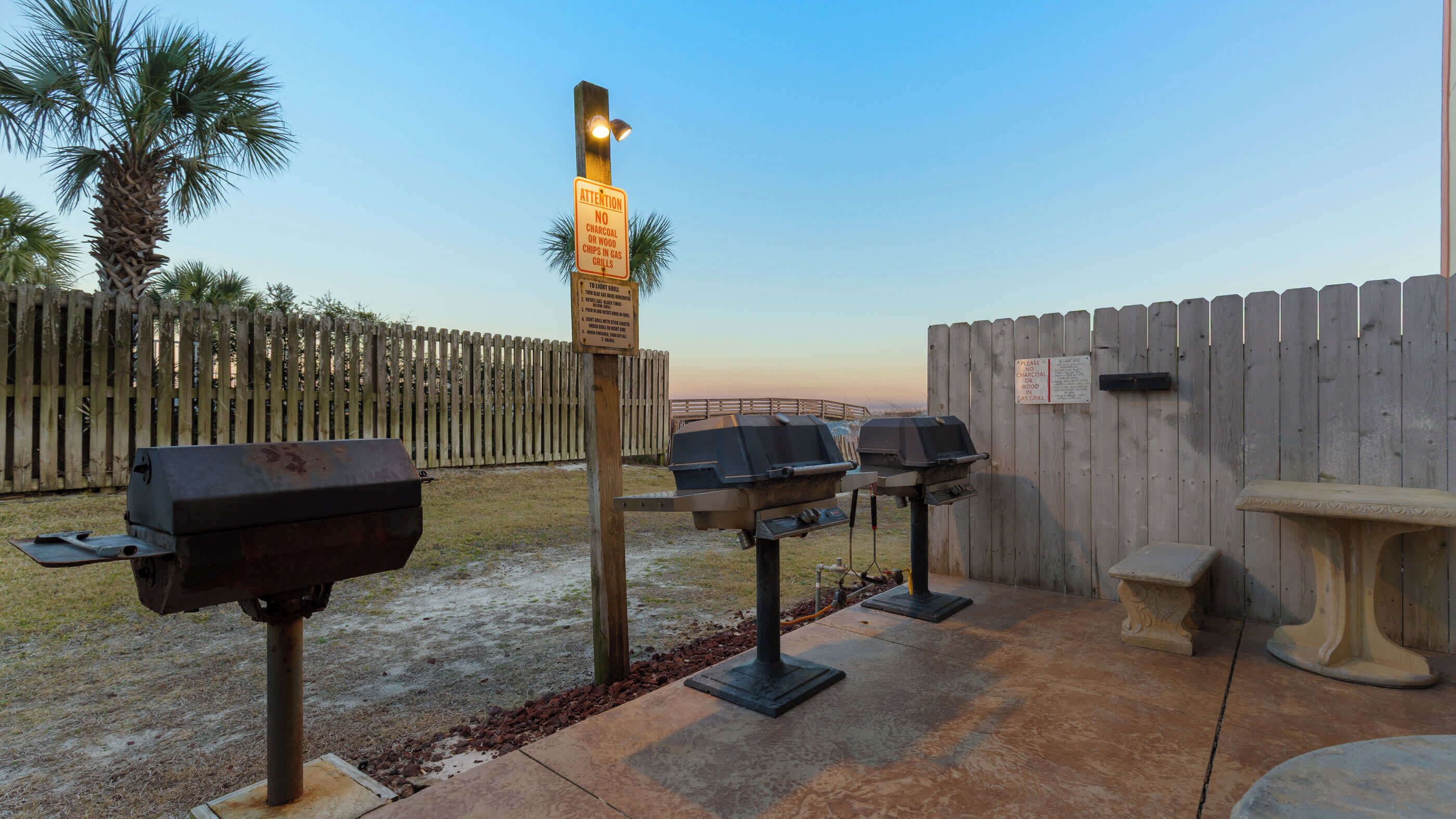 Een buitenbarbecue met barbecues en een houten omheining.