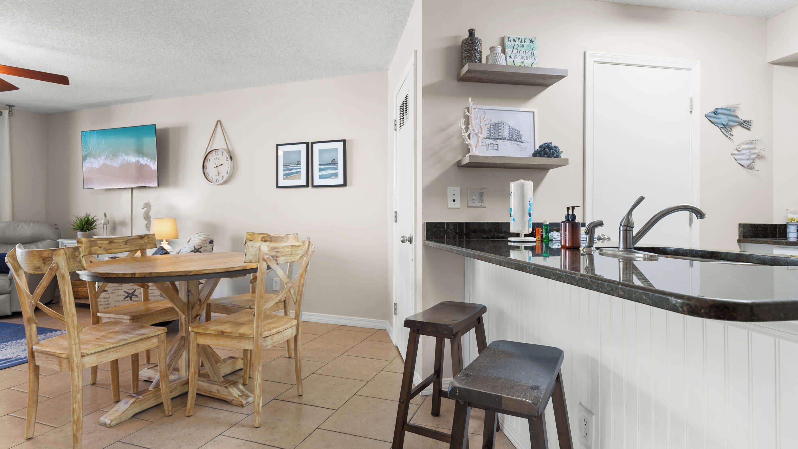 Una cucina compatta con zona pranzo, con un tavolo e sedie in legno, isola integrata con lavello e un piccolo piano di lavoro.