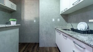 Una cocina moderna con encimeras de granito, armarios blancos y suelo de madera.
