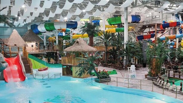 Et indendørs vandland med vandrutsjebaner, pools og tropeinspireret arkitektur.