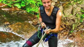 Una persona descendiendo por un arroyo rocoso usando arnés y cuerdas.