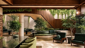 A modern interior with a curved seating area, a staircase, and greenery. - Sítio El Tropicano (San Antonio)