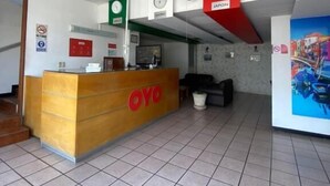 Un espace d’accueil avec un comptoir en bois portant l’inscription « OYO », un ventilateur de plafond et une horloge.