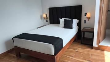 A neatly made bed with a black headboard, two bedside lamps, and a wooden nightstand.