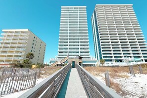 Ein modernes Hotel mit einer zentralen Treppe zum Eingang, umgeben von Sandstrand und Holzstegen.