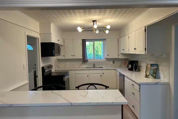 A compact kitchen with white cabinets, a central island, and a window providing natural light.