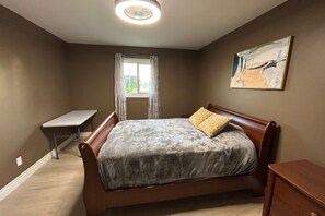 A bedroom with a bed, a desk, and a window.
