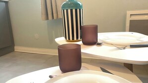A dining table with a white plate, a fork, a knife, and two brown cups. - Le 202 : studio rénové au coeur de Rouen (Rouen)